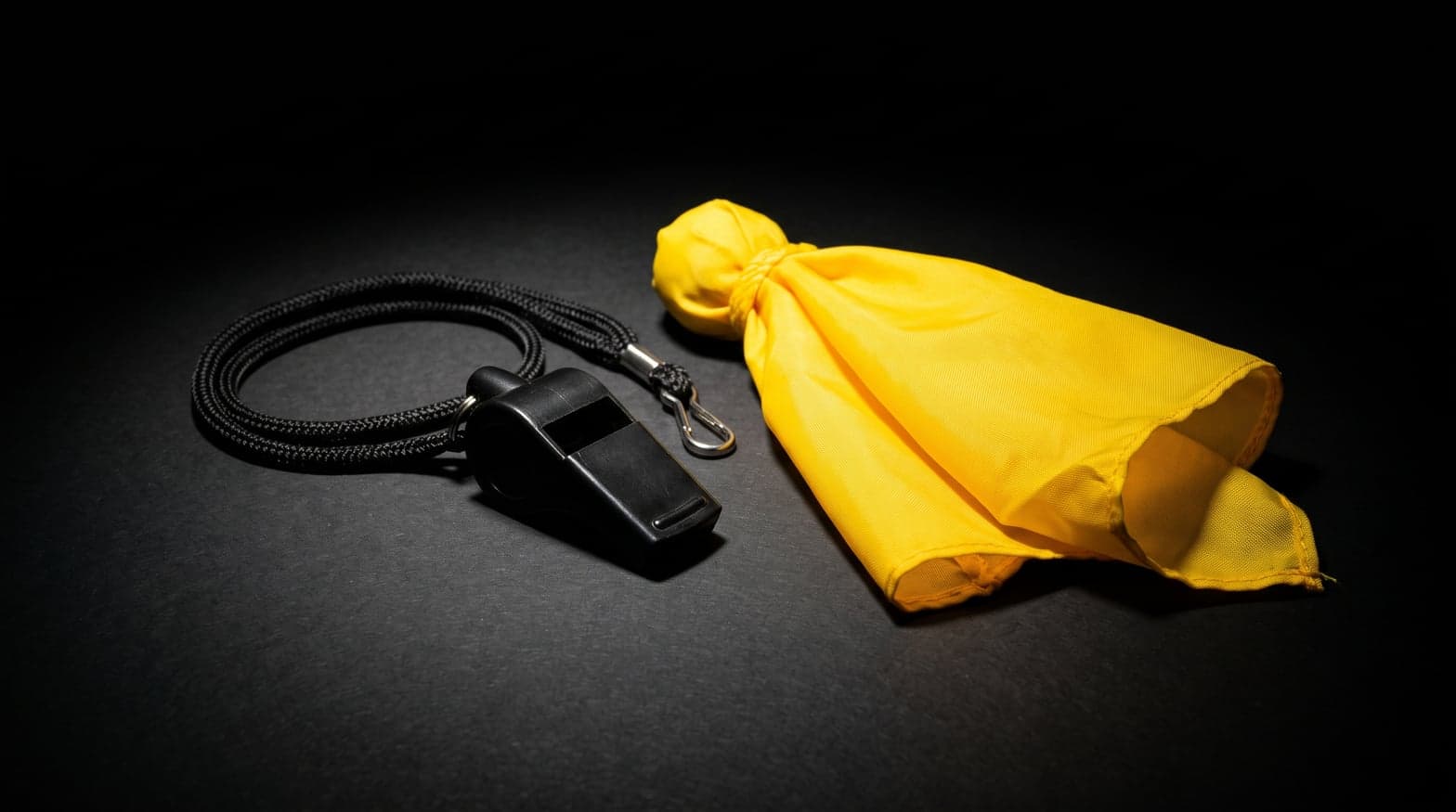 Apito preto e flag amarelo de arbitragem sobre fundo preto